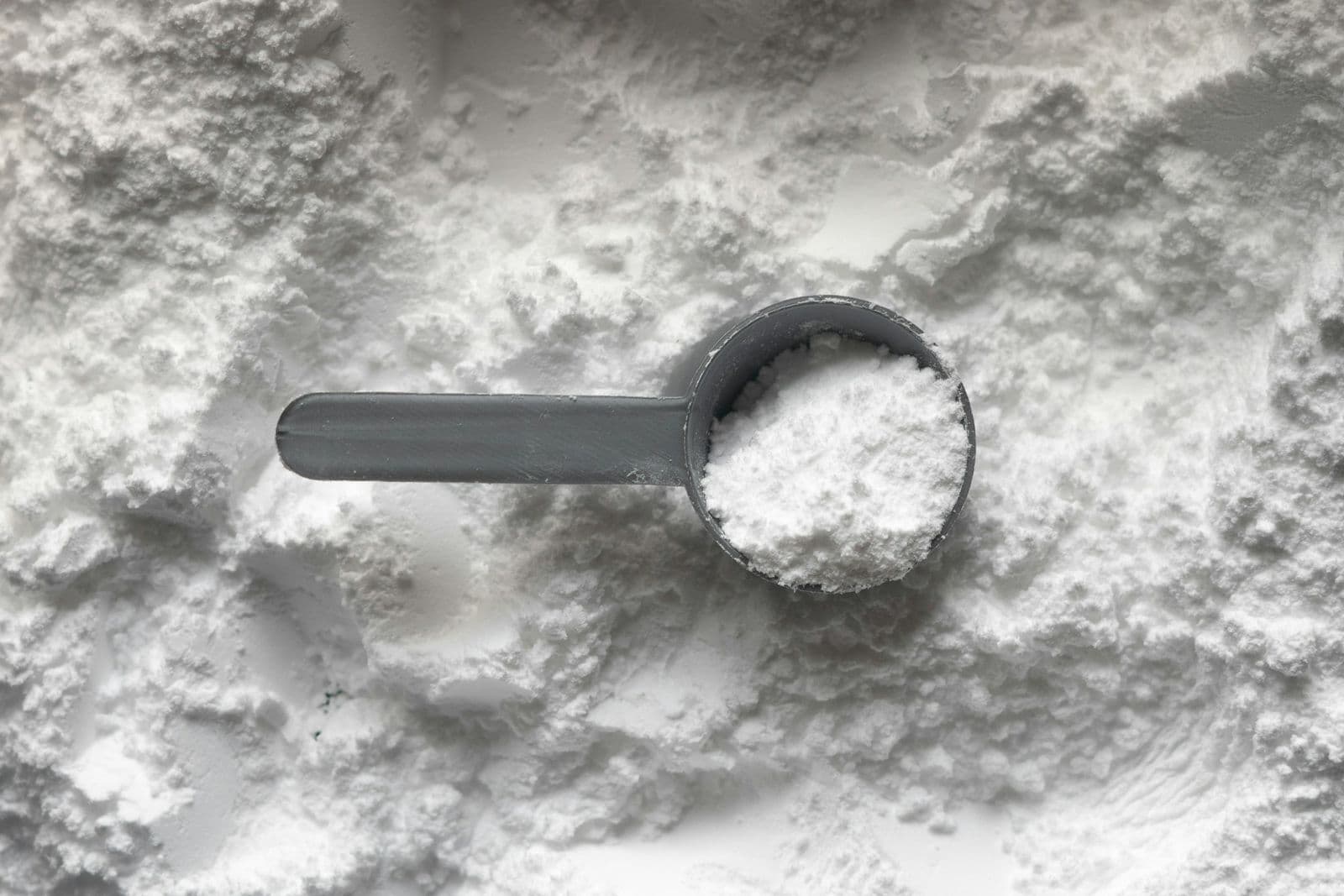 Fine white collagen powder in a measuring scoop